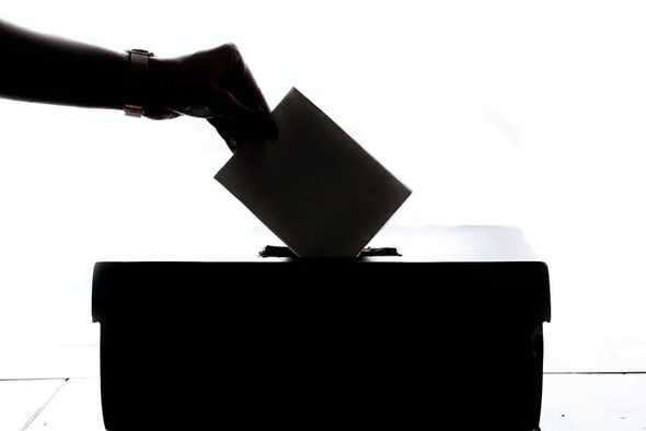 Imagem de mão depositando voto em urna