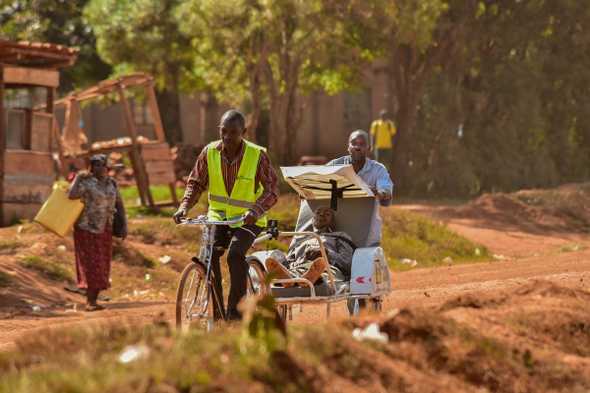 The bicycle ambulance service operates in areas where cars can not travel, with local workers ferrying people to health centres. [Nicholas Bamulanzeki/Al Jazeera]